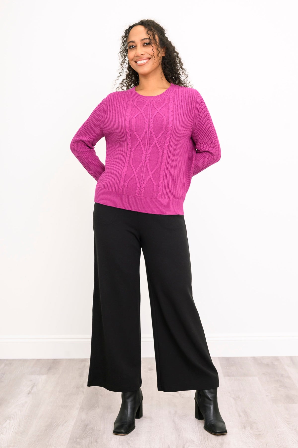 Front view of a vibrant rose-pink knit top and black trousers, highlighting a comfortable and relaxed drape.