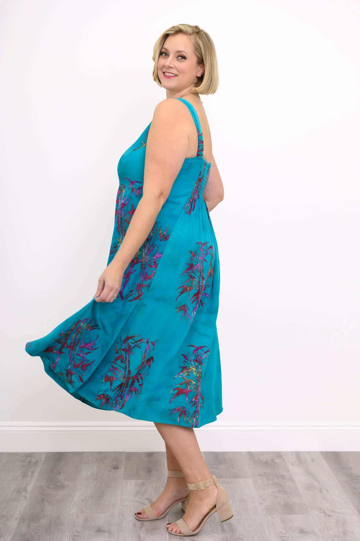 Woman spinning in a vibrant aqua blue midi dress with floral patterns