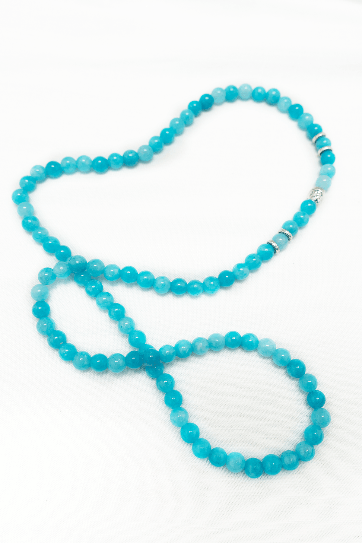 Aquamarine bead necklace with silver accents displayed on a white background