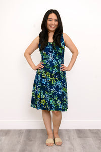 Front view woman wearing blue and green floral patterned sleeveless dress on a white background