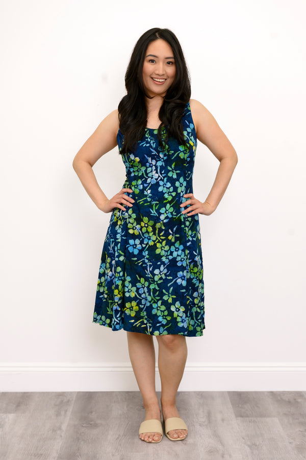 Front view woman wearing blue and green floral patterned sleeveless dress on a white background