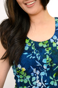 Front view woman wearing blue and green floral patterned sleeveless dress on a white background