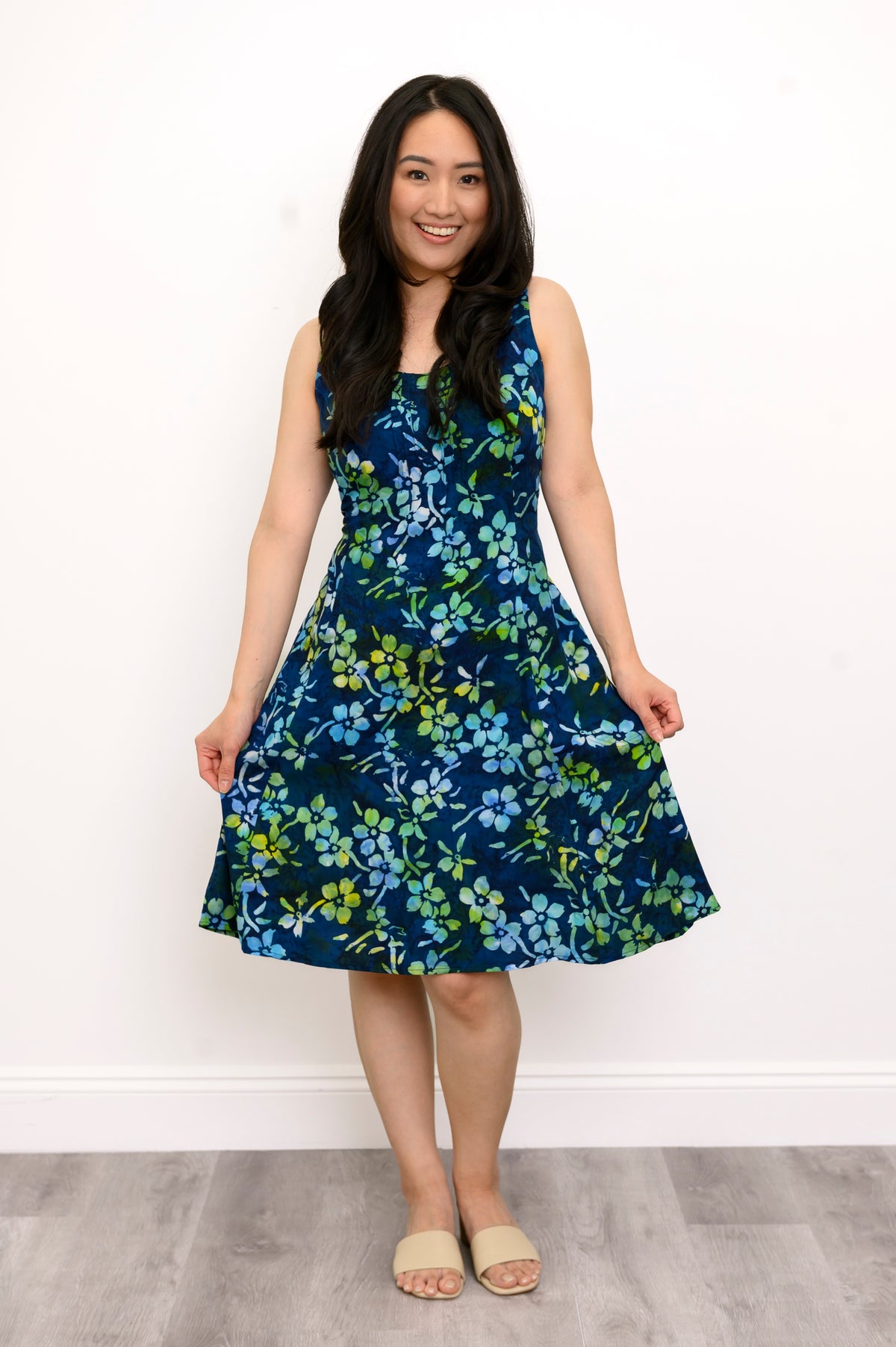 Front view woman wearing blue and green floral patterned sleeveless dress on a white background