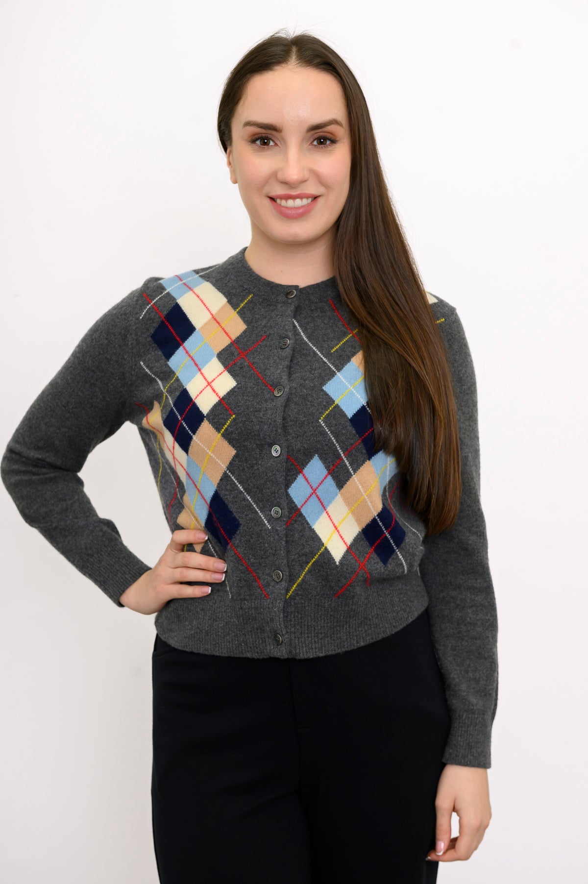 Woman wearing multicolor argyle knit sweater with black pants on a white background, front view