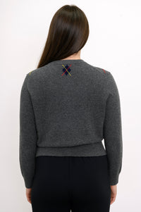 Close up back view of woman wearing grey knit sweater with ribbed hem and relaxed fit