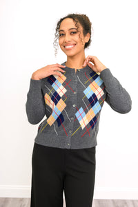 Close-up view of woman smiling and posing with her hands wearing a grey argyle sweater