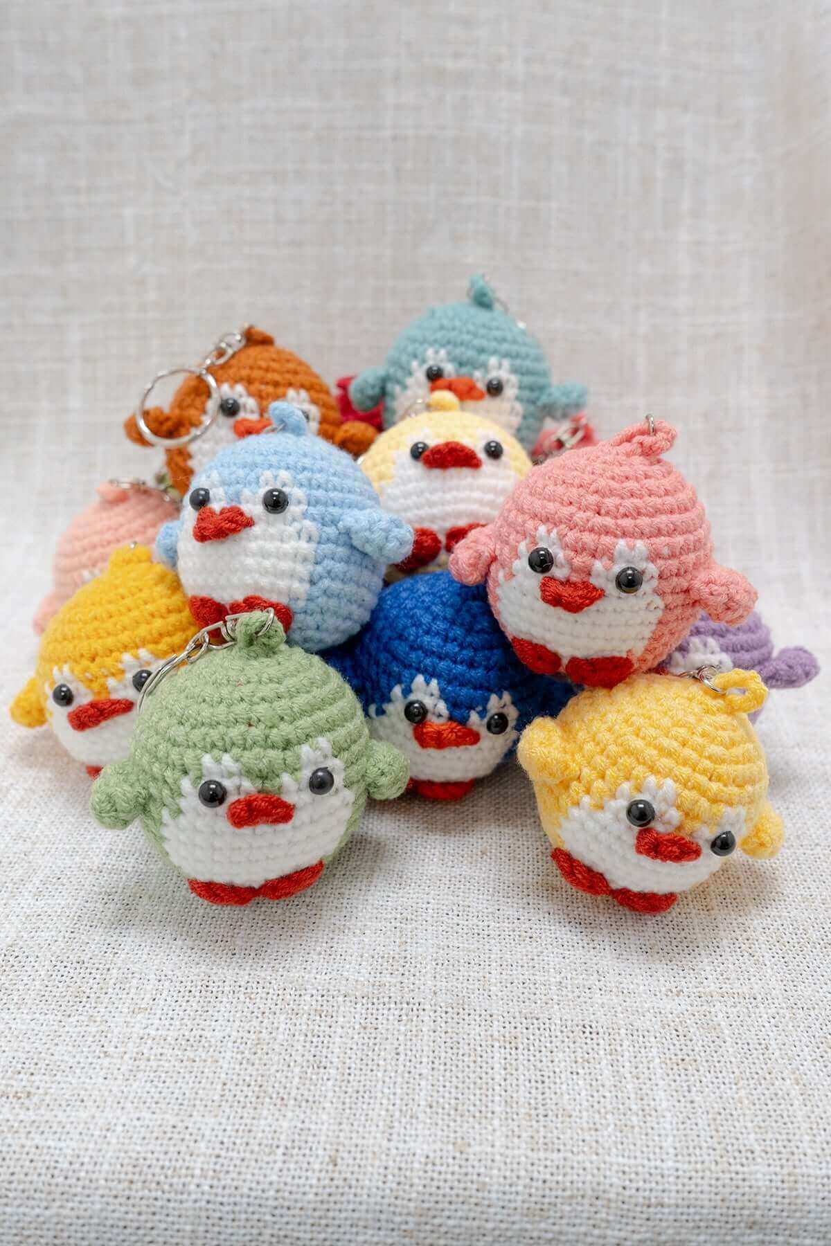 A colorful assortment of round crochet bird keychains with expressive faces and soft yarn details