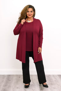 Straight-on full body view of a woman wearing an open wine red French terry cardigan with a burgundy top and black pants.