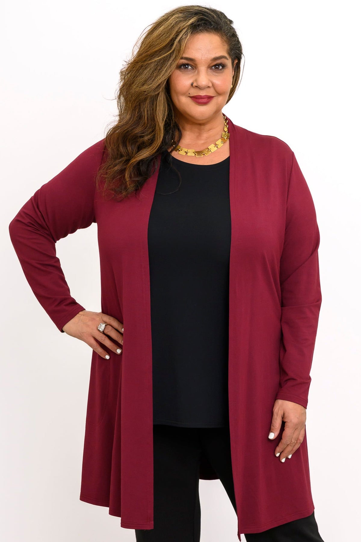 Front view of a smiling woman wearing an open burgundy long-line French terry cardigan over a black top.