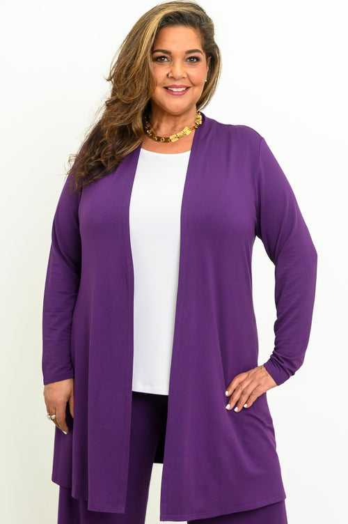 Front view of a smiling woman wearing an open royale purple long-line bamboo cardigan over a white top.