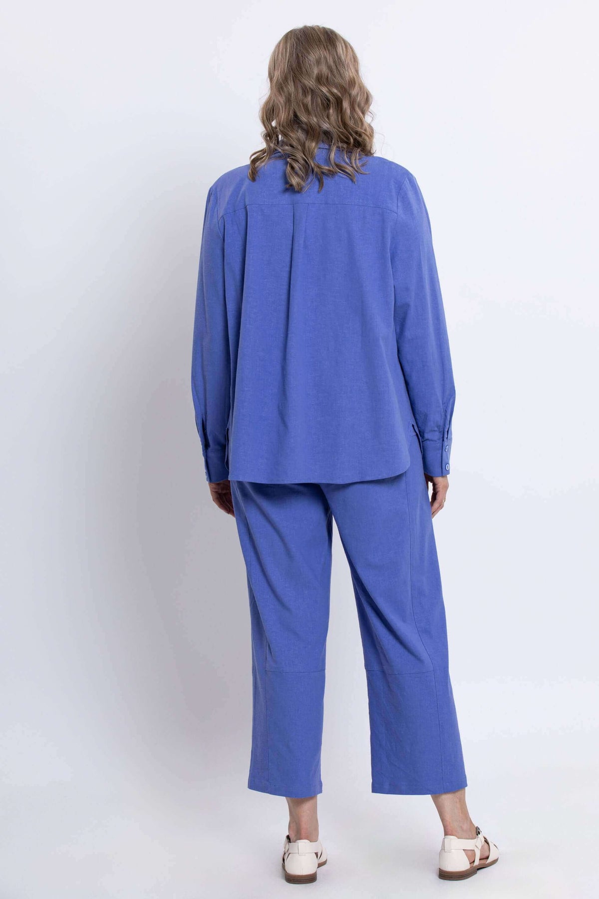 Back view of a woman wearing an azure blue relaxed shirt and matching pants set