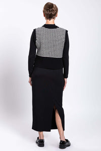 Back view of model wearing black and white striped vest with black skirt