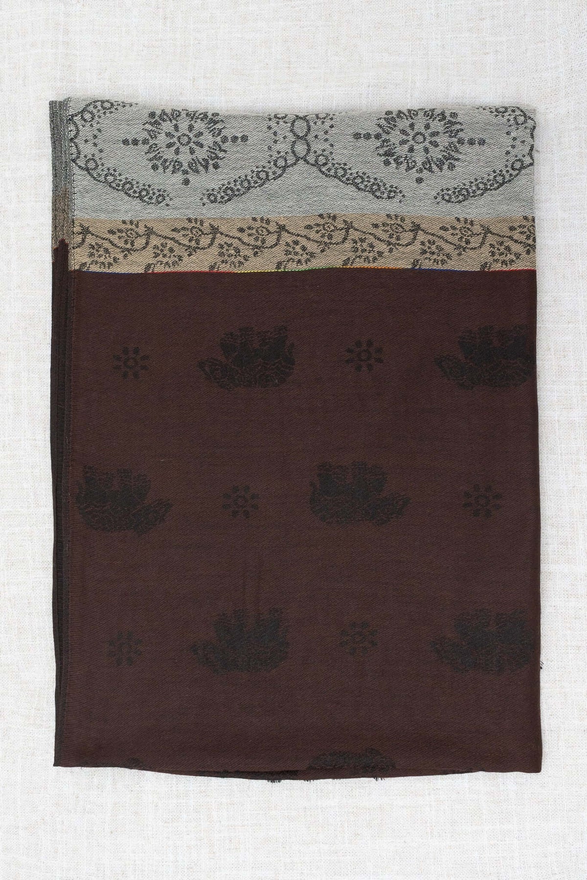 Reverse side of pashmina scarf showing brown base with subtle dark floral patterns and borders