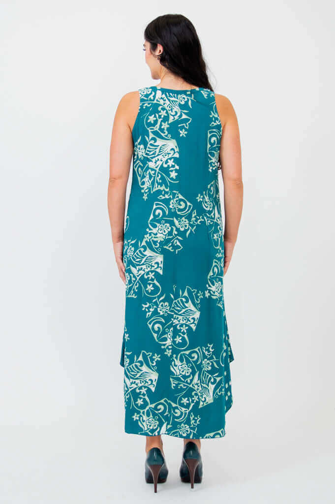 Back view of woman in teal sleeveless dress with white botanical print and midi length