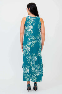 Back view of woman in teal sleeveless dress with white botanical print and midi length