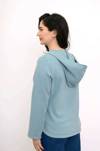 Back and side view of a woman wearing a light blue hoodie jacket