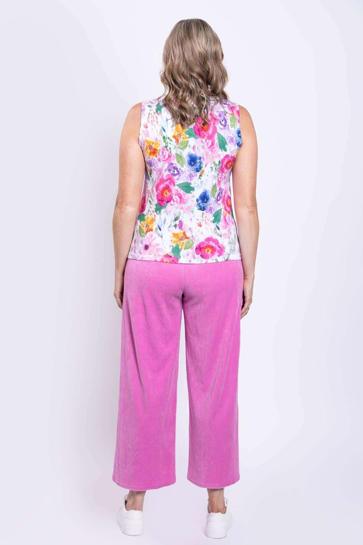 Back view of a woman wearing a floral tank top with wide straps and pink pants