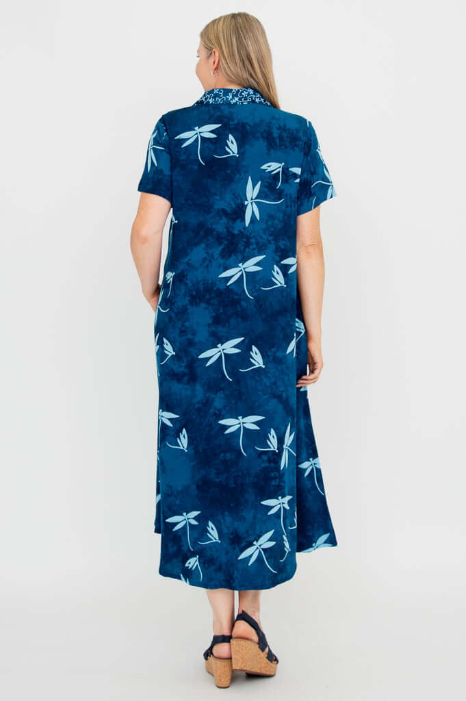 Back view of woman in a blue short sleeve dress with dragonfly motif and flared hem