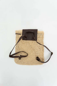 Back view of the woven backpack showing brown adjustable straps and handle