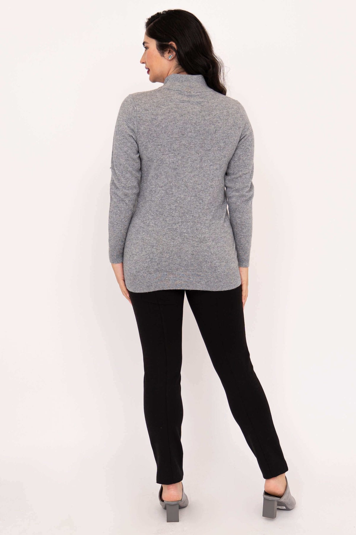 Back view of woman wearing a grey long sleeve mock neck sweater with a hi-lo hem