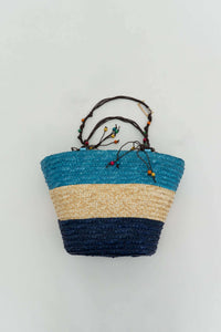 Back view of rattan tote showing blue, beige, and navy color blocking with beaded handles