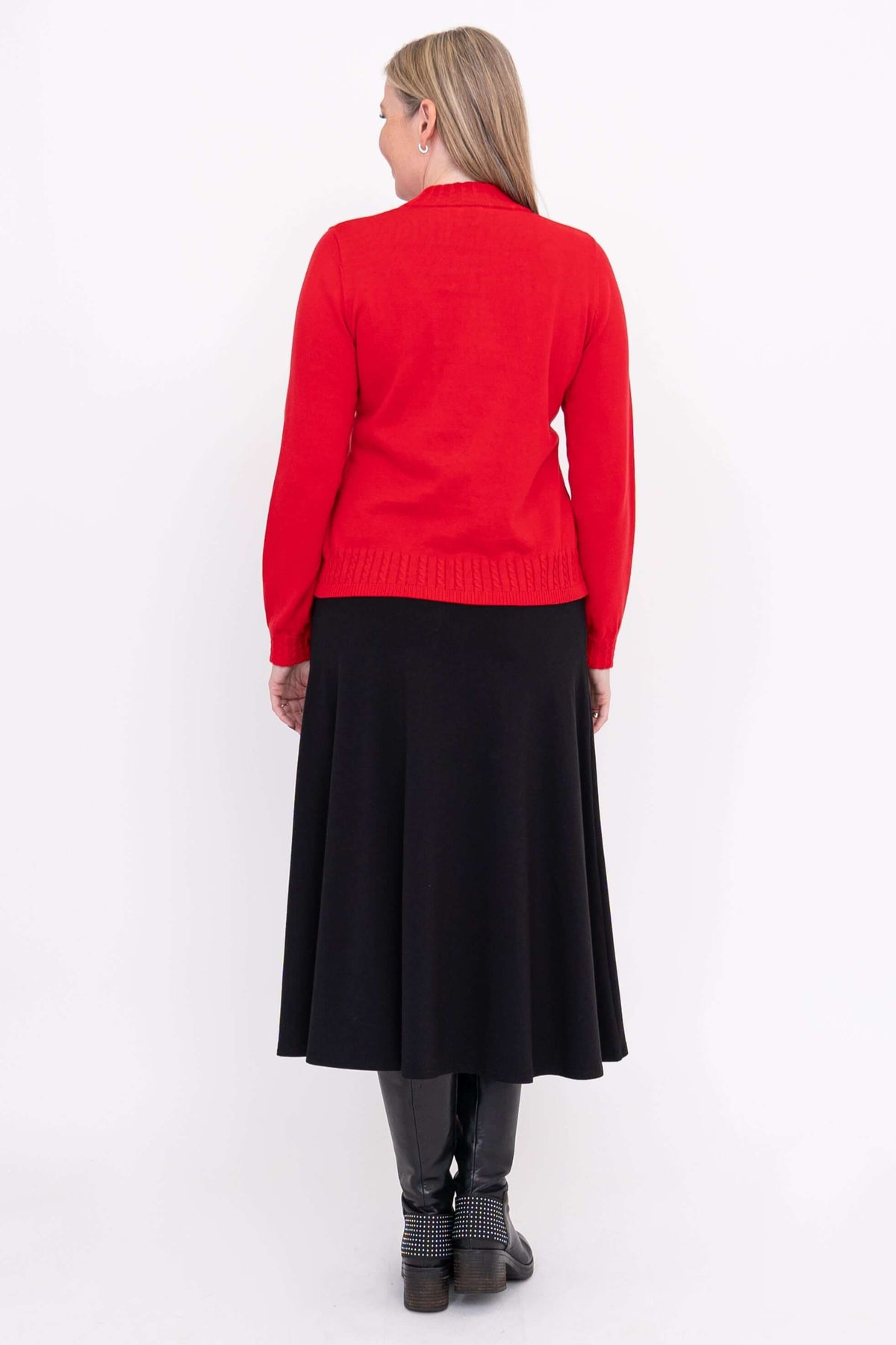 Back view of woman in red mock neck sweater and black skirt, with studded black boots