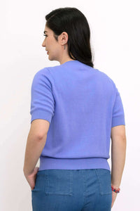 Back view of a woman in a purple short sleeve cardigan and blue pants