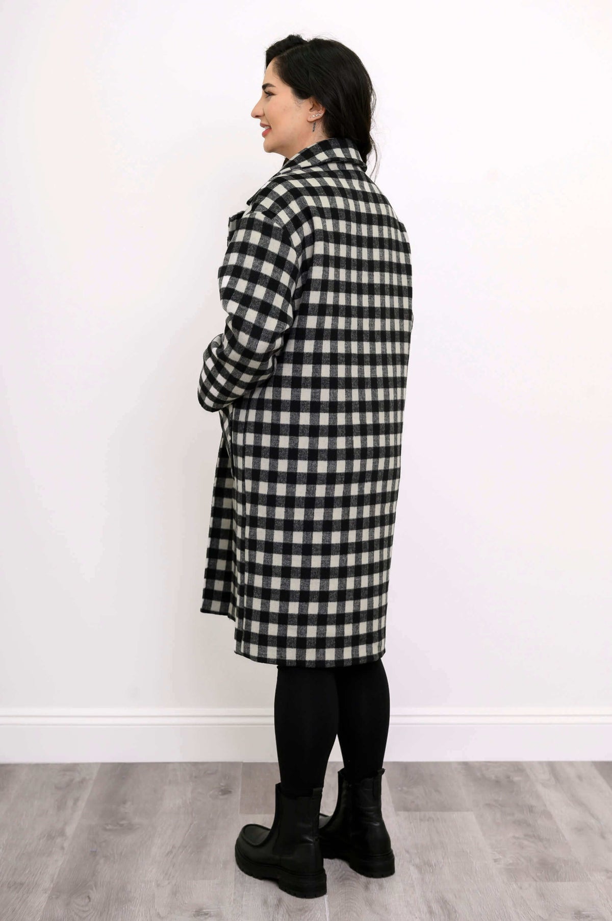 Back side view of model wearing mid-length black and white check coat
