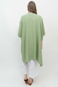 Back view of sage green kimono wrap draped over woman in white outfit