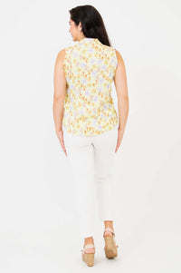 Back view of model wearing yellow sleeveless floral shirt and white pants