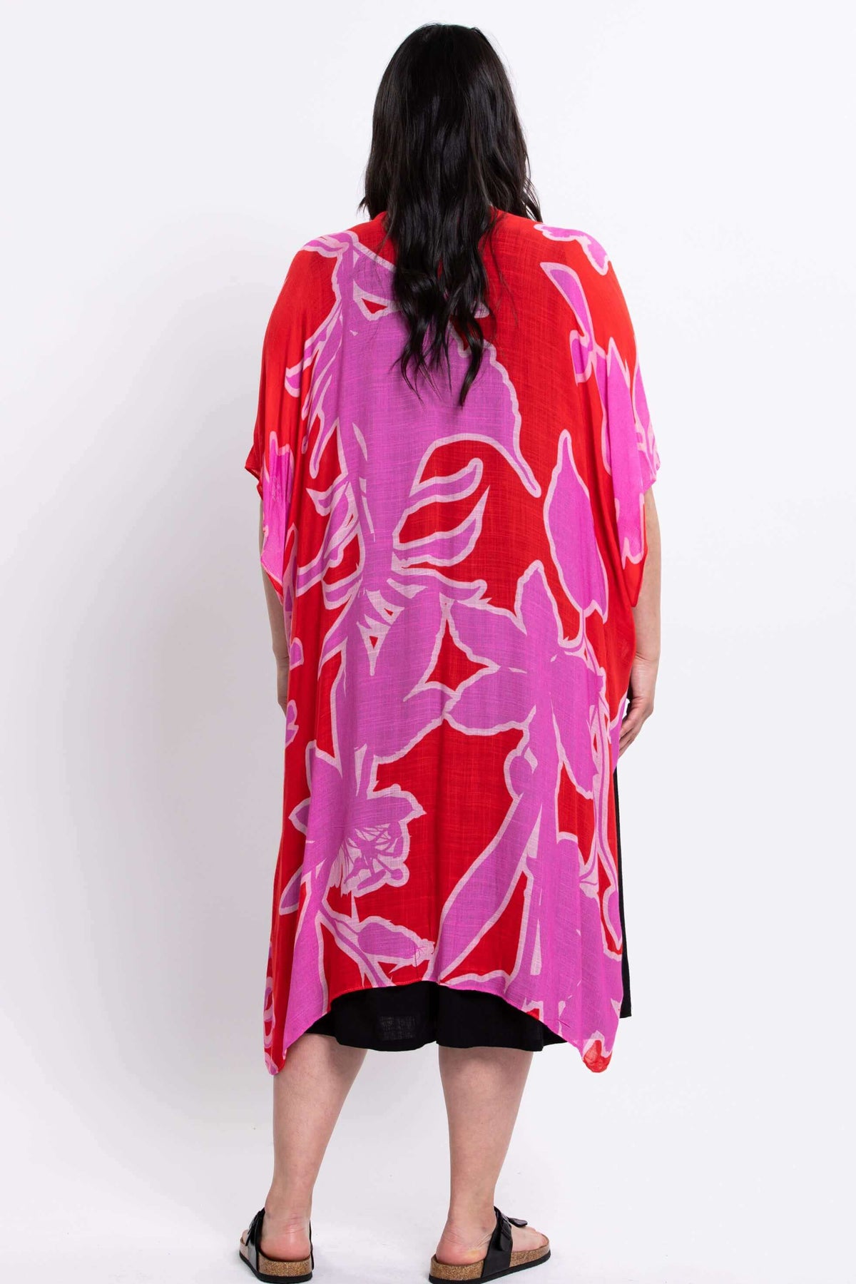 Back view of a woman wearing a pink and red floral kimono wrap over a black dress