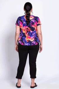 Back view of model wearing Ritzy Short Sleeve Top with vivid abstract print