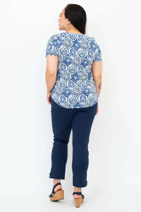 Back view of woman wearing blue mosaic Tessa Tee and navy cropped pants