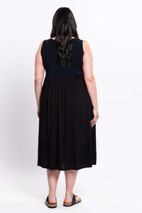 Back view of model in a black sleeveless empire waist midi dress showing full length