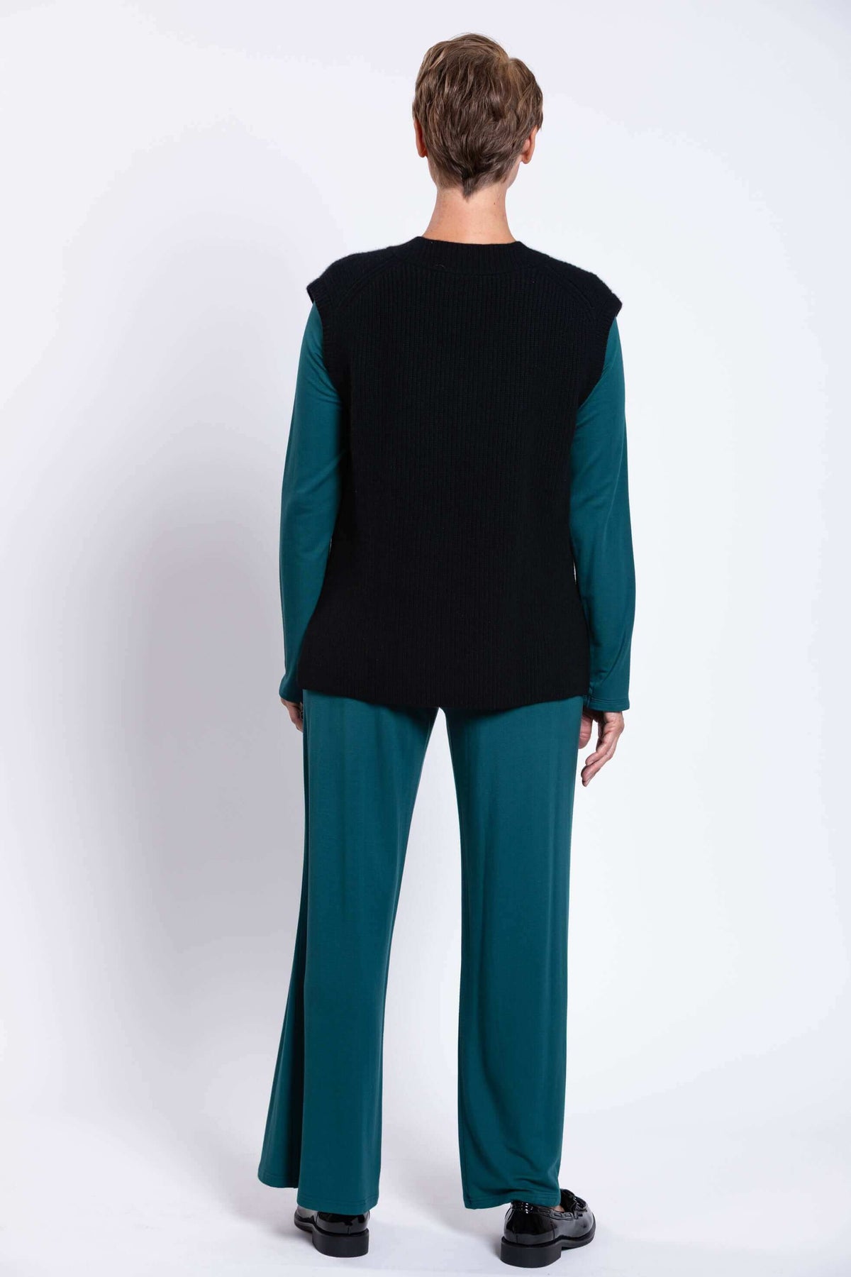 Back view of woman wearing black wool-cashmere vest and teal wide-leg pants