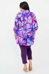 Back view of model wearing oversized floral tunic in vibrant purple and pink hues
