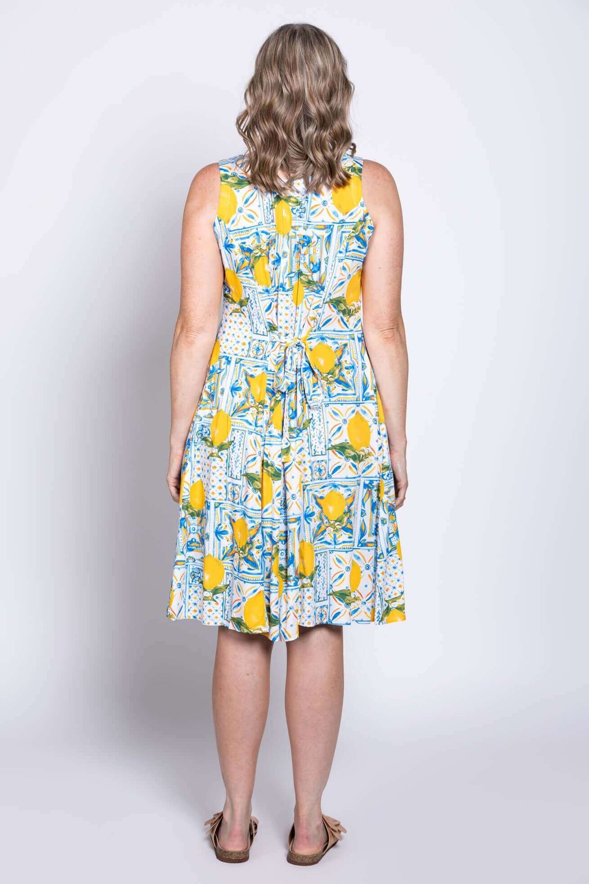 Model wearing Arden dress with lemon tile print, showing rear tie detail, back view