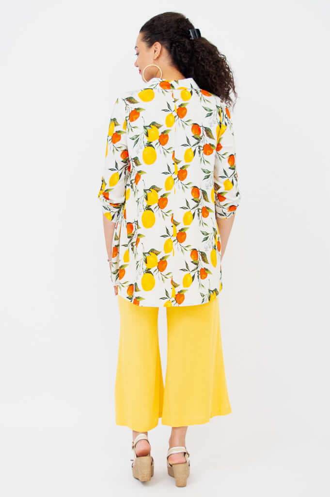 Back view of model in citrus print tunic and yellow wide-leg pants