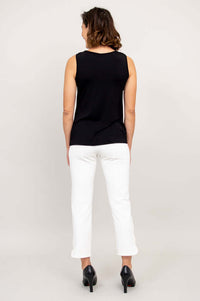 Back view of a woman wearing a black sleeveless cowl neck top with white pants