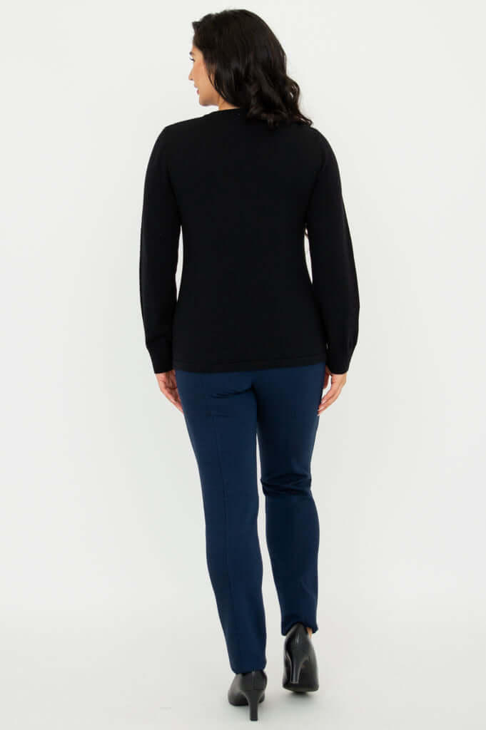 Back view of model wearing black sweater with long sleeves and navy pants