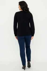 Back view of model wearing black sweater with long sleeves and navy pants