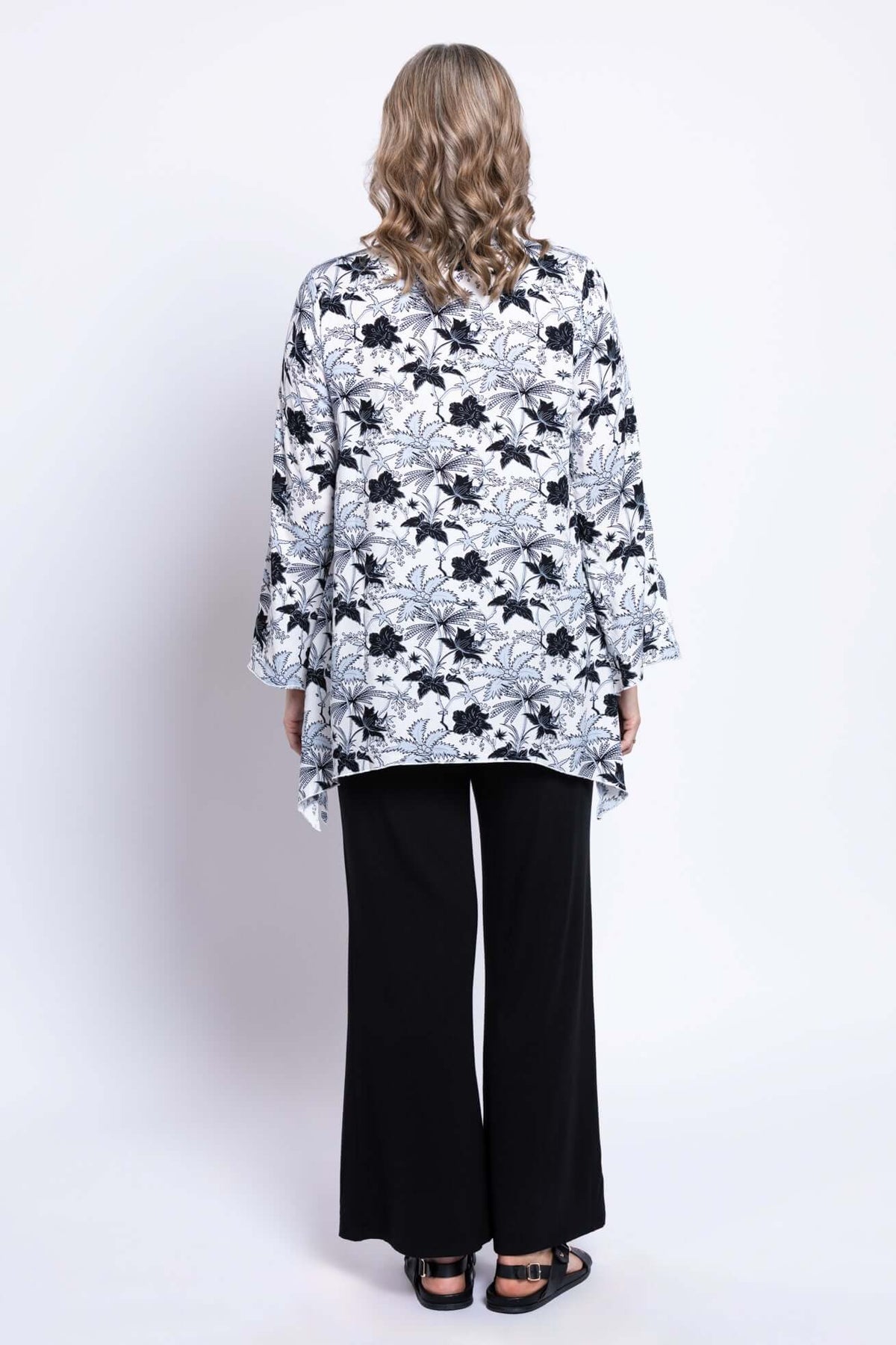 Back view of model showing flowy hemline of floral boho top