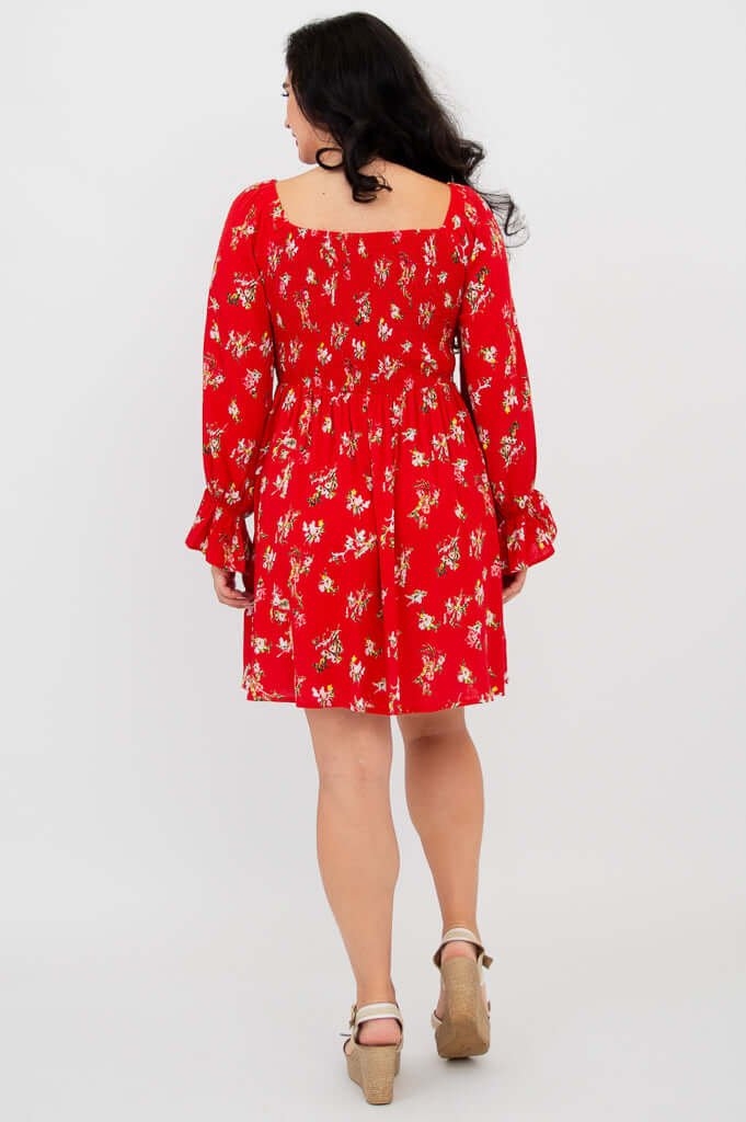 Back view of a model wearing a red ditsy print dress with a gathered bodice