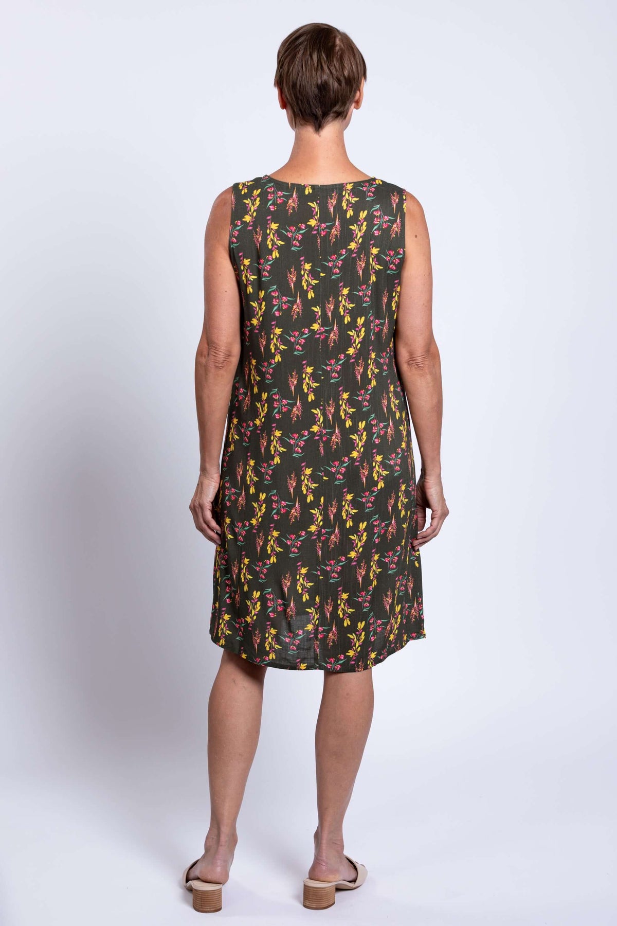 Back view of woman wearing green floral sleeveless shift dress