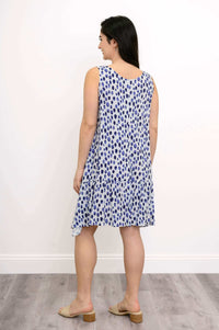 Back view of woman in sleeveless blue polka dot dress with ruffle detail