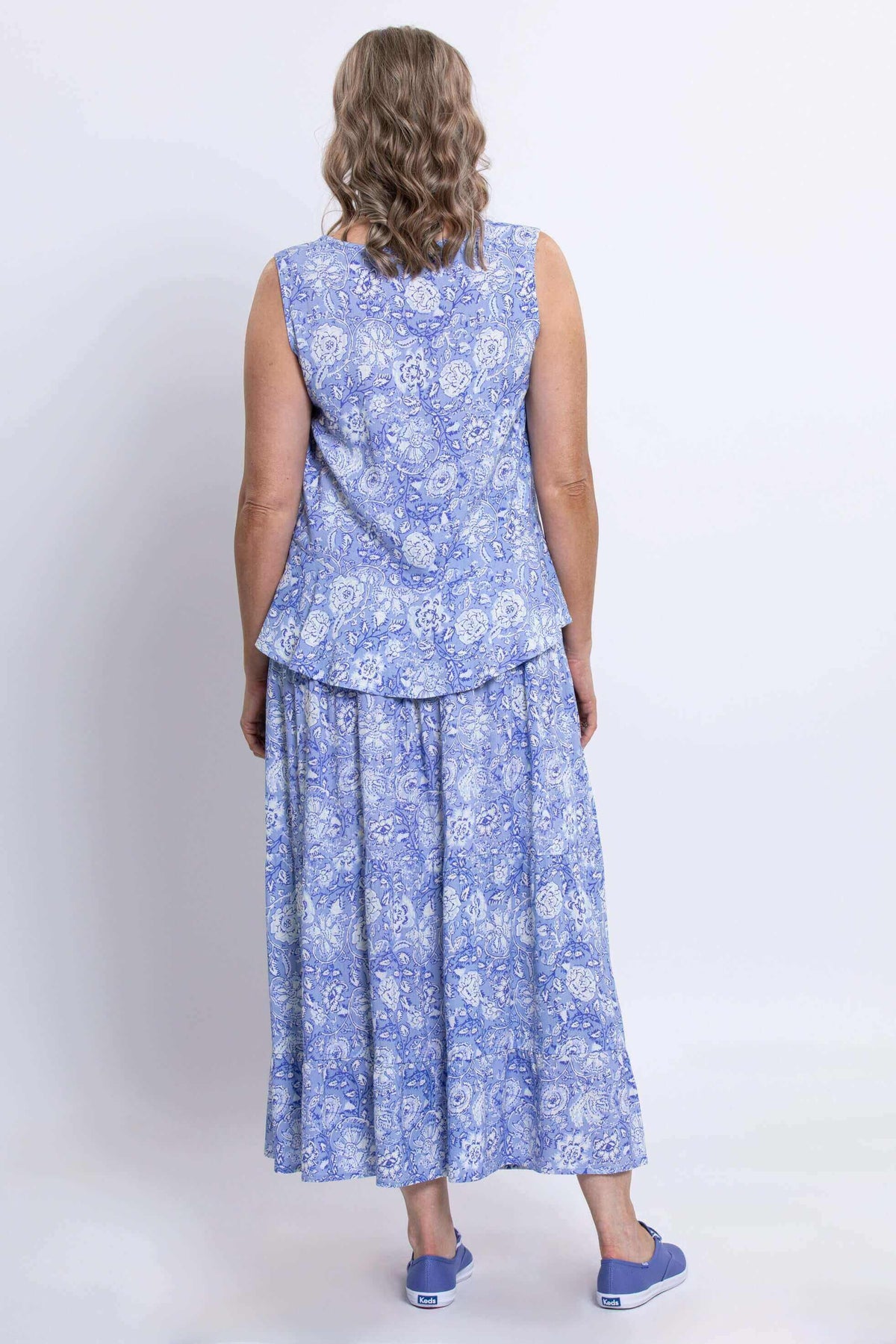 Back view of woman wearing blue floral Ginny tank top and matching skirt