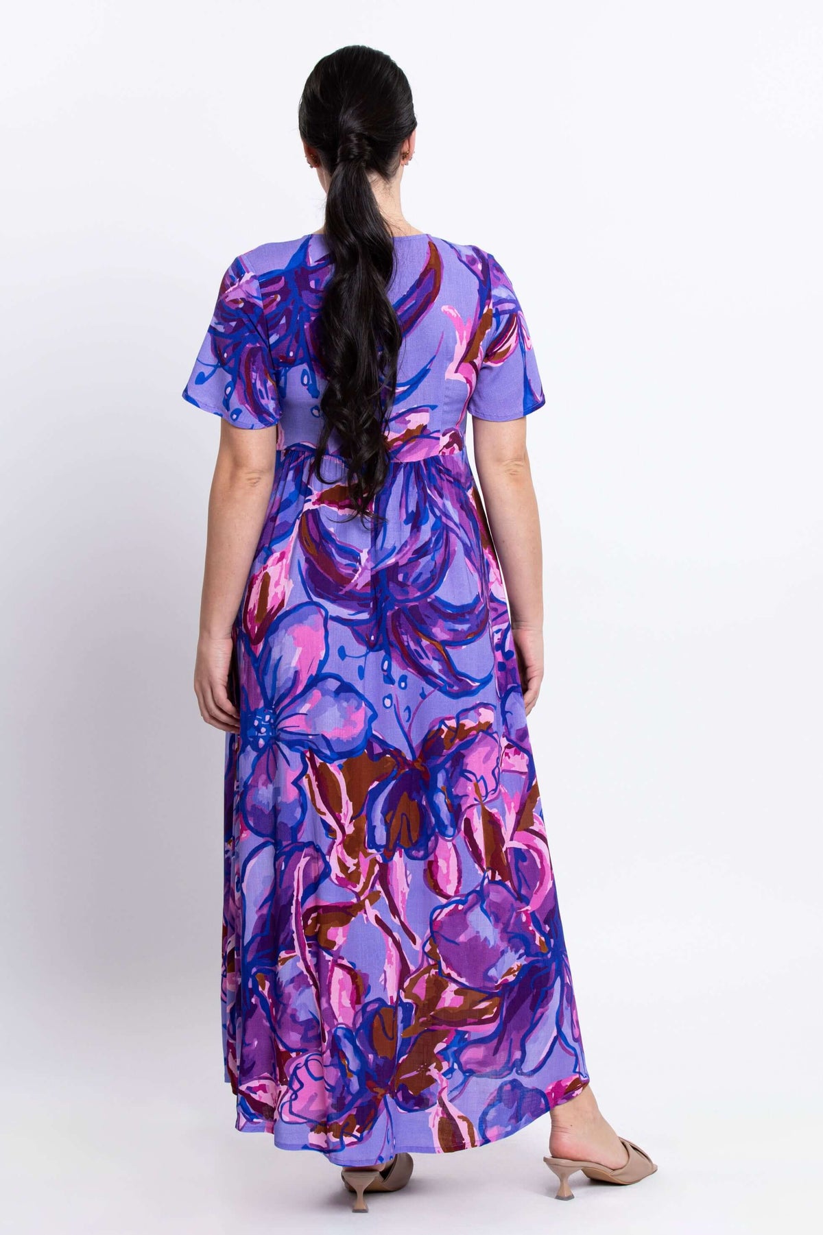 Back view of a woman in a flowing purple floral print maxi dress with short sleeves