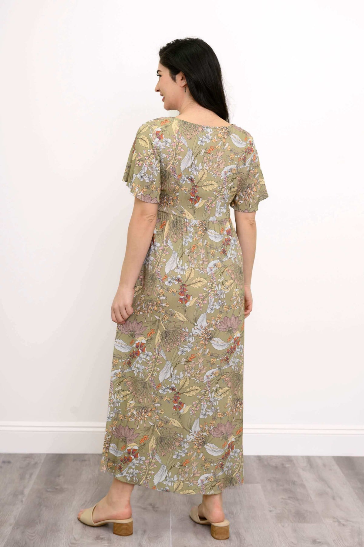 Back view of woman wearing green floral Jane empire waist maxi dress