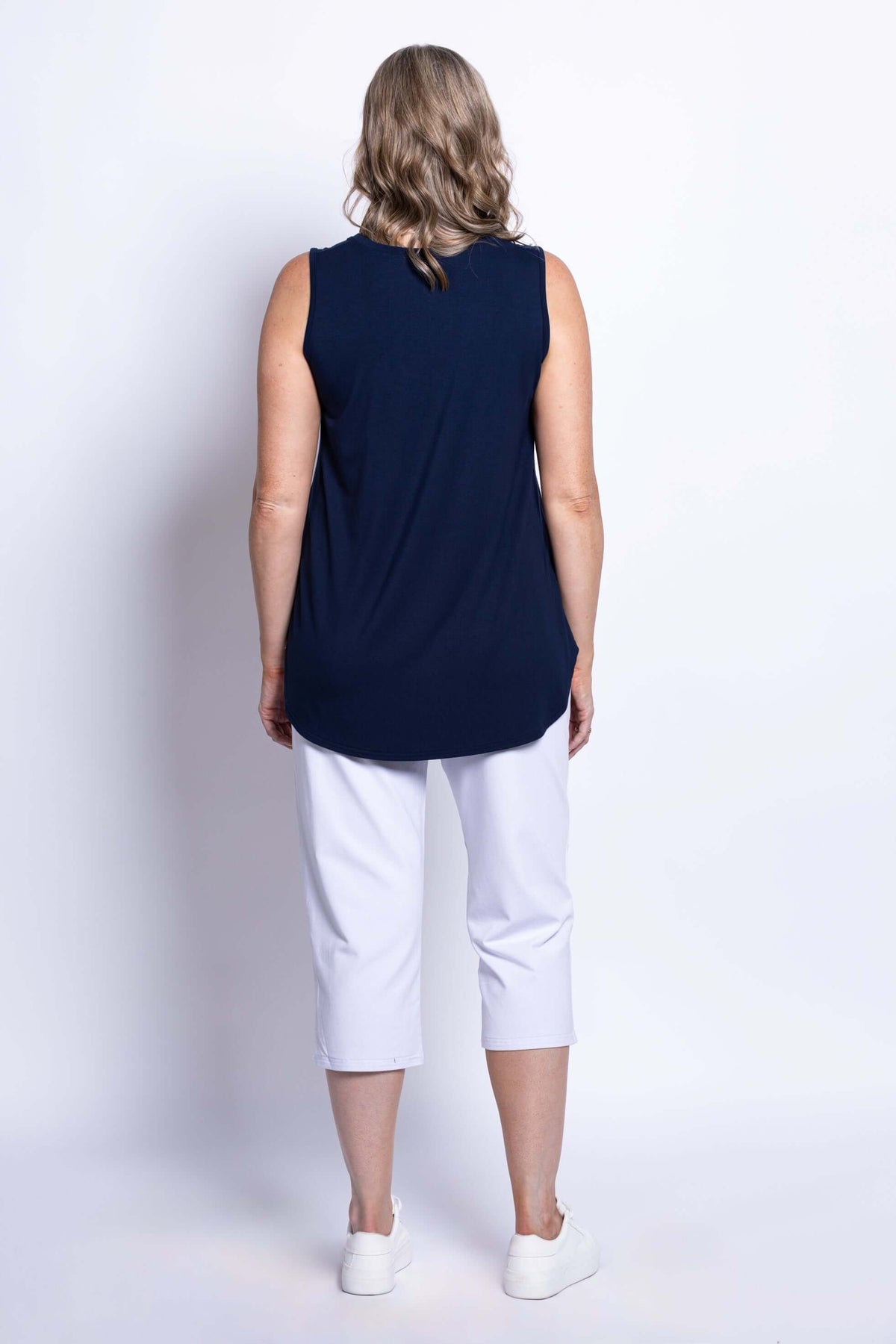 Back view of woman in navy bamboo tank top and white cropped pants