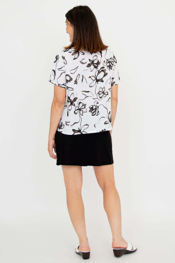 Back view of model wearing white floral short sleeve collared top